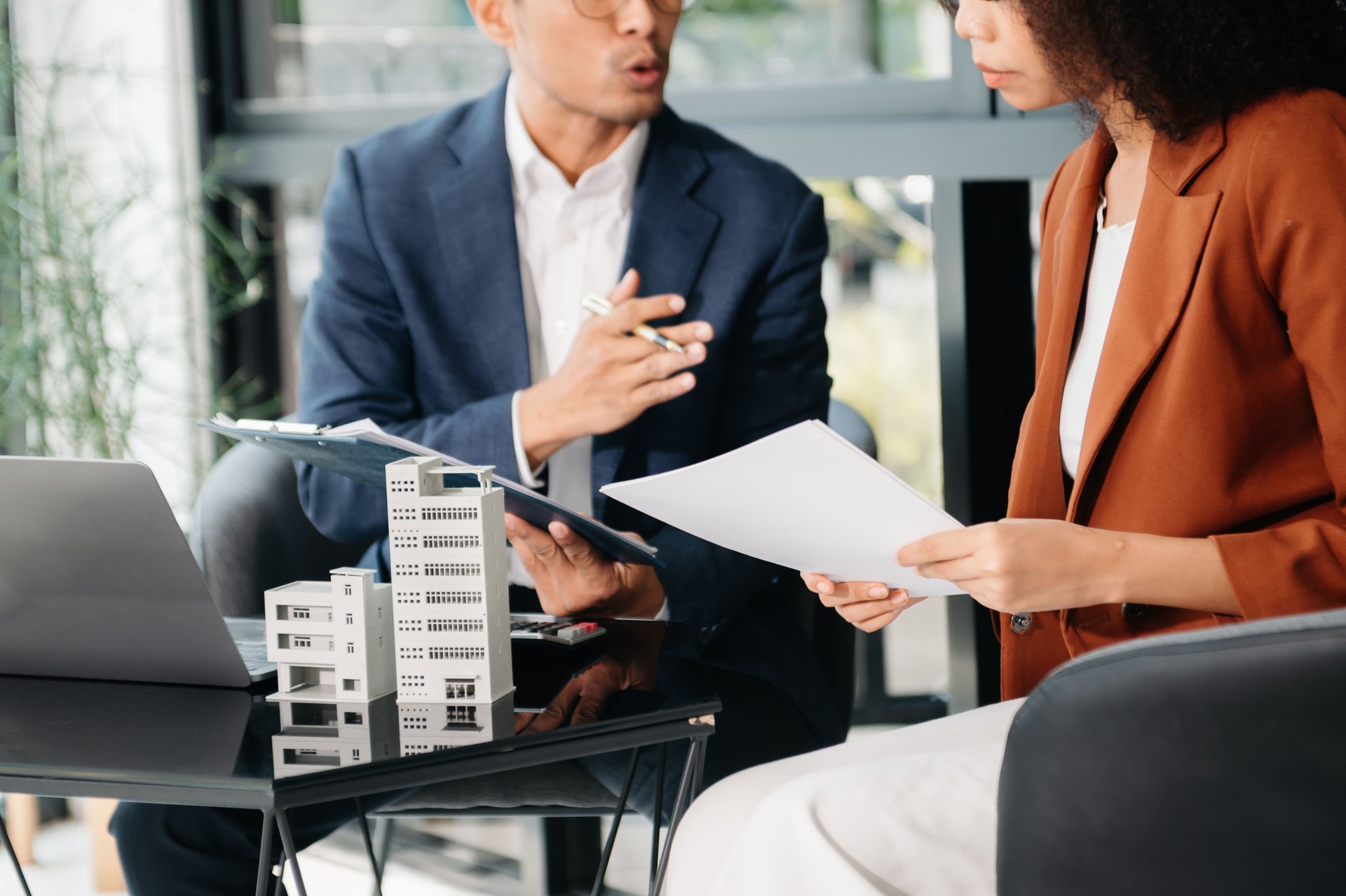 Real estate broker agent presenting and consult to customer to decision making sign insurance form agreement, home model, concerning mortgage loan offer